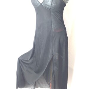 May include: Black slip dress with a V-neck and spaghetti straps. The dress features a high slit on the side and a flowing, sheer skirt. The bodice has a textured appearance. A simple, elegant design.