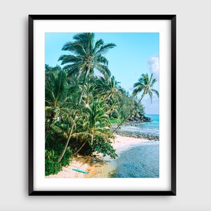 May include: A photograph of a tropical beach scene with palm trees, a sandy shore, and turquoise water. A blue surfboard lies on the sand.
