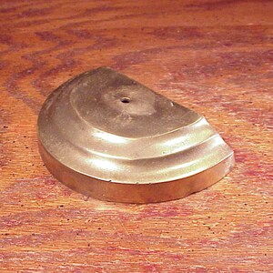 May include: A gold-colored metal base with a half-circle shape and a decorative, fluted edge.