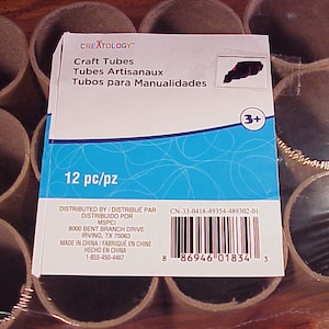 May include: A pack of 12 brown cardboard craft tubes, labelled "Craft Tubes" in blue and white text. The pack also includes the text "Tubes Artisanaux" and "Tubos para Manualidades". The pack is labelled "12 pc/pz" and has a barcode and a "3+" age recommendation.