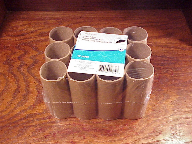 May include: A pack of 12 brown cardboard craft tubes, wrapped in clear plastic. The pack is labelled "Craft Tubes - Tubos Artesanales - Tubes pour Manualidades" and "12 Pops".
