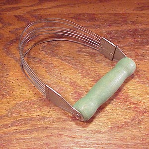 May include: A vintage pastry blender with a light green wooden handle and stainless steel blades. The blades are curved and attached to a rectangular metal frame. The handle is cylindrical and painted a light green color. The tool is designed for mixing ingredients.