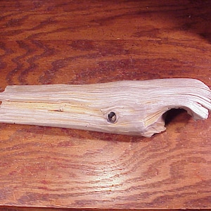 May include: A light brown driftwood whale sculpture with a hole in the side. The whale is carved from a piece of wood with a natural, weathered finish.