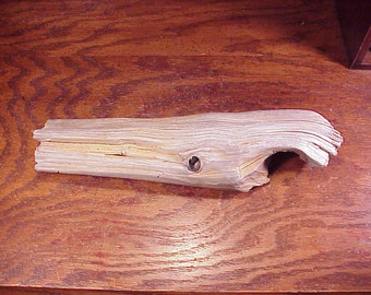 May include: A light brown driftwood whale sculpture with a hole in the side. The whale is carved from a piece of wood with a natural, weathered finish.