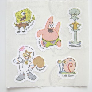 May include: A set of five stickers featuring characters from the animated television series Spongebob Squarepants. The stickers feature Spongebob, Patrick Star, Squidward Tentacles, Sandy Cheeks, and Gary the Snail. The stickers are all on a white background and have the copyright information "© 2001 Viacom" printed on them.