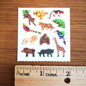 Könnte beinhalten: Eine Blatt mit bunten Tieraufklebern auf weißem Hintergrund. Die Aufkleber zeigen eine Vielzahl von Tieren, darunter einen Tiger, eine Giraffe, einen Affen, einen Gorilla, ein Chamäleon, einen Tukan, einen Löwen, ein Warzenschwein, einen Panther und einen Vogel. Die Aufkleber sind etwa 2,5 cm groß.