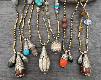 May include: Nine gold chain necklaces with various pendants, including turquoise, agate, and bone. Each necklace features a unique charm and bead combination.