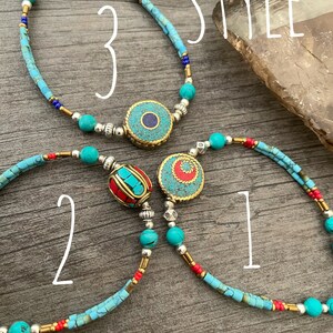 Puede incluir: Tres pulseras de cuentas de color turquesa y plata con diferentes dijes. Los dijes son un dije redondo de turquesa y plata, un dije redondo de turquesa y oro, y un dije rojo y oro. Las pulseras est&aacute;n etiquetadas como "Estilo 1", "Estilo 2" y "Estilo 3".