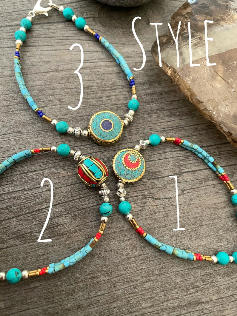 Puede incluir: Tres pulseras de cuentas de color turquesa y plata con diferentes dijes. Los dijes son un dije redondo de turquesa y plata, un dije redondo de turquesa y oro, y un dije rojo y oro. Las pulseras est&aacute;n etiquetadas como "Estilo 1", "Estilo 2" y "Estilo 3".