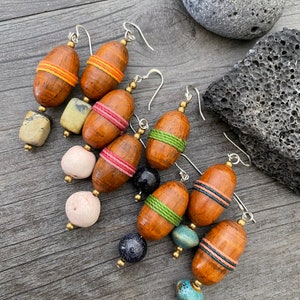 May include: A collection of handcrafted earrings featuring wooden acorn-shaped beads with colorful thread accents. The earrings have silver-colored ear wires and are paired with various stone and bead combinations. The wooden beads are approximately 1 inch in length.