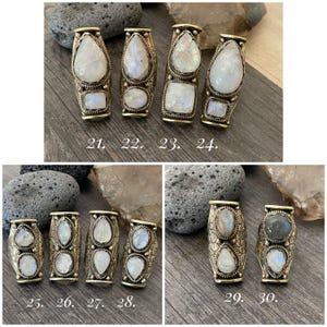 May include: Ten silver rings with moonstone settings. Each ring has a different design and features a unique moonstone. The rings are numbered 21 through 30.