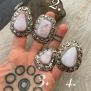 May include: Four silver rings with pink stones set in ornate designs. The rings are numbered 1 through 4.