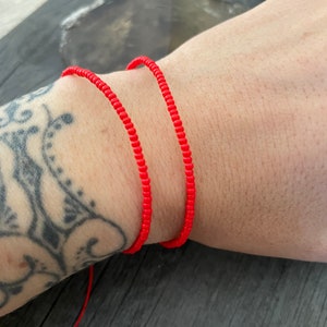 May include: A red beaded bracelet with a string tie closure.
