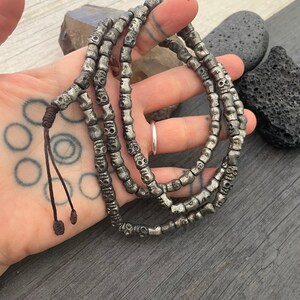 May include: A silver skull bead necklace with a brown leather cord. The necklace is made of many small skull beads and is about 18 inches long.