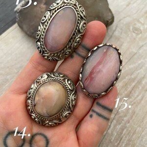 May include: Three silver rings with pink and white gemstone settings. The rings are numbered 13, 14, and 15.