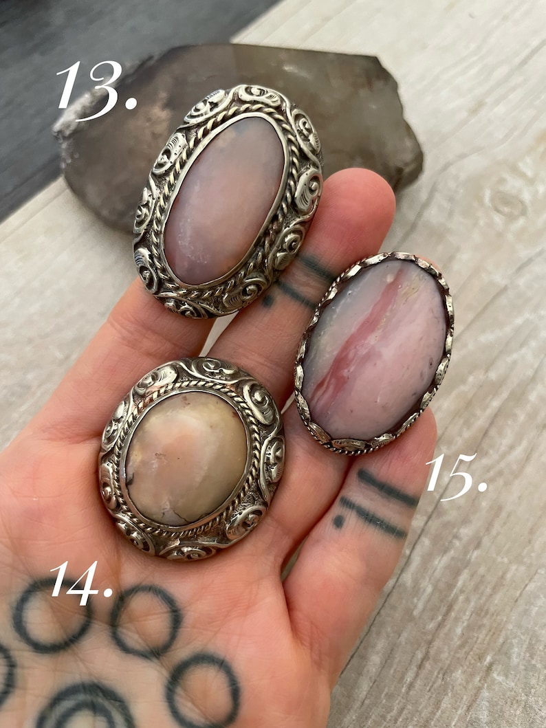 May include: Three silver rings with pink and white gemstone settings. The rings are numbered 13, 14, and 15.