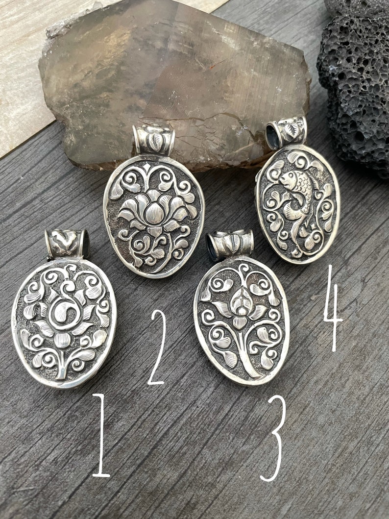 May include: Four silver pendants with intricate floral and fish designs. The pendants are numbered 1 through 4.