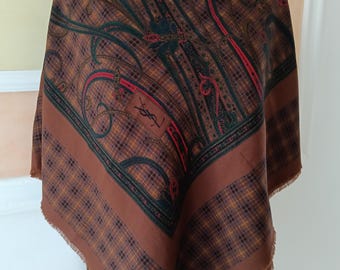 May include: Brown and green paisley scarf with a plaid border. The scarf features a repeating paisley pattern in shades of brown, green, and red. The border has a plaid design in similar colors. The scarf has a fringed edge and a logo.
