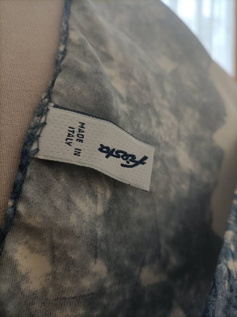 May include: Close-up of a fabric with a blue and white pattern. A label with the word "Fiesta" and "MADE IN ITALY" is visible. The fabric has a textured appearance.