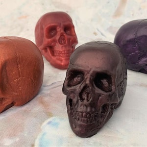 Four skulls facing all different directions.  Shown in pics are bronze (front right facing left), red wine (back row facing forward), black-red (front right facing forward) and (back right facing the right) eggplant purple skull.