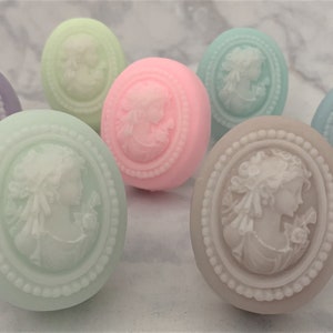 An oval mini soap featuring the illustration of a sophisticated woman facing in one direction, rendered in soft pastel colors of your choice with white highlights that enhance her elegance and charm.