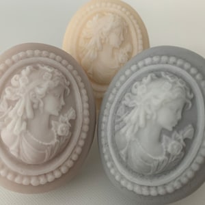 An oval mini soap featuring the illustration of a sophisticated woman facing in one direction, rendered in soft pastel colors of your choice with white highlights that enhance her elegance and charm.