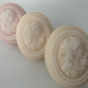 An oval mini soap featuring the illustration of a sophisticated woman facing in one direction, rendered in soft pastel colors of your choice with white highlights that enhance her elegance and charm.