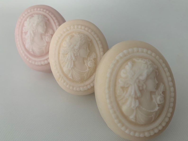 An oval mini soap featuring the illustration of a sophisticated woman facing in one direction, rendered in soft pastel colors of your choice with white highlights that enhance her elegance and charm.