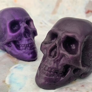 Two translucent skulls facing inward.  Back left skull facing the right is called purple galaxy which is a dark bright shade of purple like a old school purple crayon.  The front left skull is facing towards the left and is purple eggplant colored.