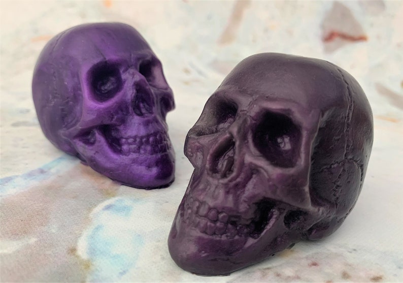 Two translucent skulls facing inward.  Back left skull facing the right is called purple galaxy which is a dark bright shade of purple like a old school purple crayon.  The front left skull is facing towards the left and is purple eggplant colored.