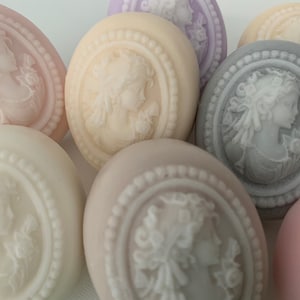 An oval mini soap featuring the illustration of a sophisticated woman facing in one direction, rendered in soft pastel colors of your choice with white highlights that enhance her elegance and charm.