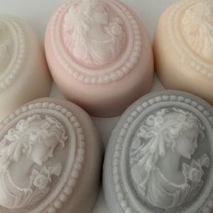 An oval mini soap featuring the illustration of a sophisticated woman facing in one direction, rendered in soft pastel colors of your choice with white highlights that enhance her elegance and charm.