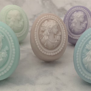 An oval mini soap featuring the illustration of a sophisticated woman facing in one direction, rendered in soft pastel colors of your choice with white highlights that enhance her elegance and charm.