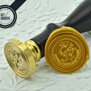May include: A gold-toned brass stamp with a design of two intertwined letters "E" and "K" with the words "Forever and Always" around the letters. The stamp is on a black wooden handle and is used to create wax seals.