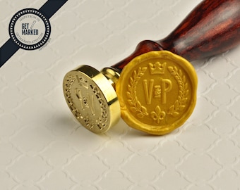 Può includere: Un timbro per sigilli in cera dorata con manico in legno. Il timbro presenta un design con una corona, una corona di alloro e le iniziali "V & P".