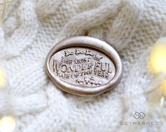 May include: A gold wax seal with the text "The Most Wonderful Time of the Year" embossed on it. The seal is sitting on a white knitted fabric.