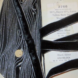May include: Black velvet ribbon with silver metallic trim. The ribbon is woven and has a taffeta back. The label reads "2768 Made in Switzerland 90% Rayon 10% Lurex Taffeta Back Velvet Woven Black/Silver Registration Nr. RN 18100 10 yards Black/Silver GRAYBLOCK 16 W. 36 th. Str. N."