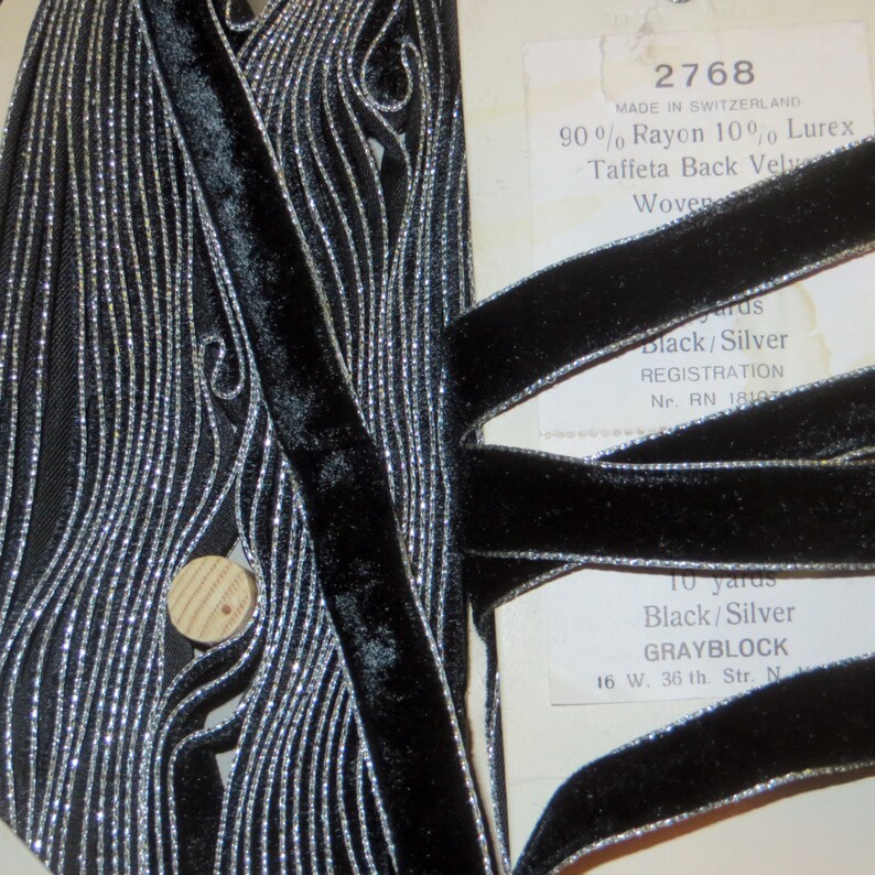 May include: Black velvet ribbon with silver metallic trim. The ribbon is woven and has a taffeta back. The label reads "2768 Made in Switzerland 90% Rayon 10% Lurex Taffeta Back Velvet Woven Black/Silver Registration Nr. RN 18100 10 yards Black/Silver GRAYBLOCK 16 W. 36 th. Str. N."