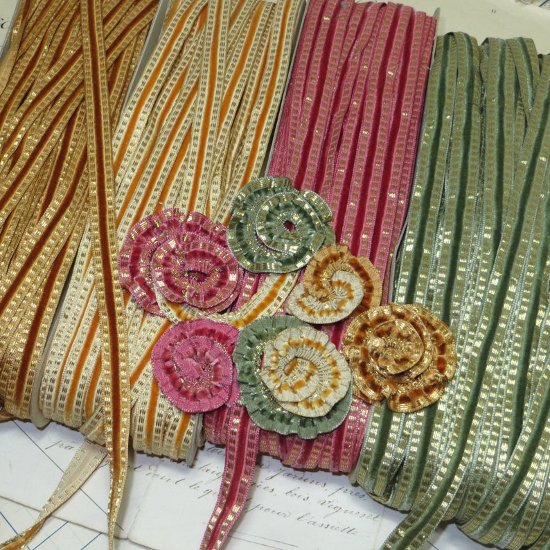 May include: Four spools of ribbon with gold trim. The ribbons are in shades of gold, green, pink, and cream. The ribbons are decorated with gold and silver trim. The ribbons are arranged in a row, with the gold ribbon on the left and the cream ribbon on the right.