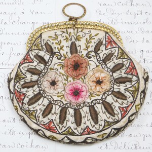May include: A white fabric purse with a gold metal frame and pearl accents. The purse is decorated with embroidered flowers in shades of pink, red, and brown.