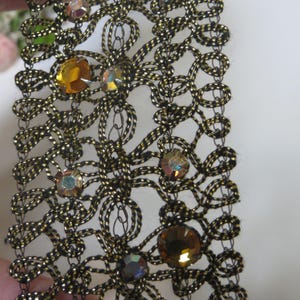 May include: Black and gold trim lace with iridescent and amber colored rhinestones.