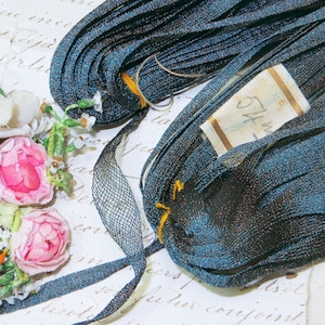 May include: Two spools of teal blue metallic trim with gold thread. The spools are labeled "5/16" in black ink.