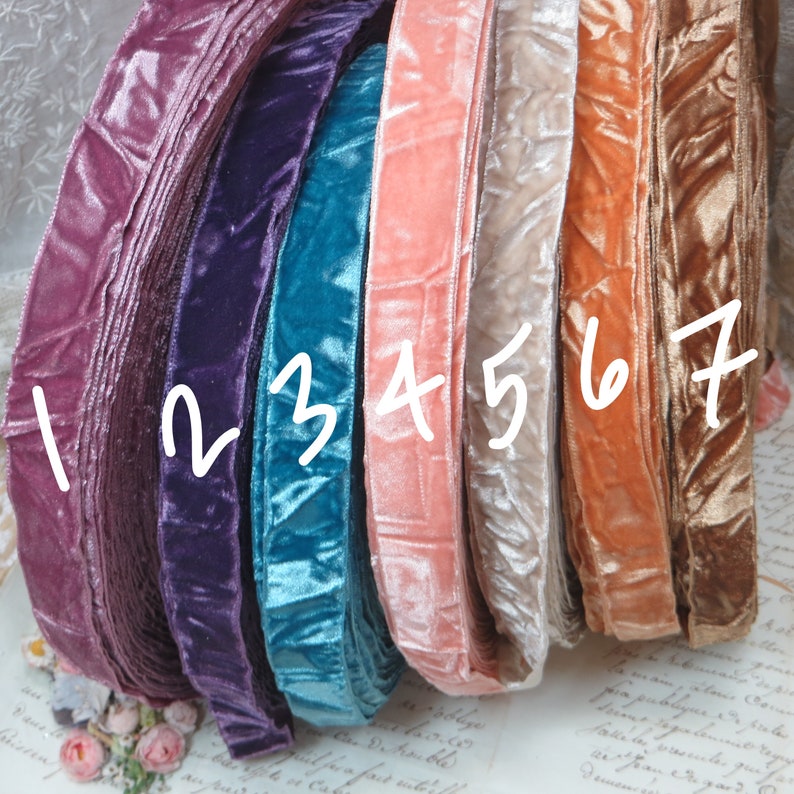 May include: A collection of velvet ribbon in a spectrum of colours, from deep purple to teal, peach, and gold. The ribbon is rolled, displaying its soft texture and sheen. The image showcases the variety of colours suitable for crafting or decorative use.