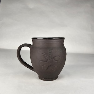16 oz Flying "luck" mug black clay with black glazing.  Handmade pottery. Roman. Fascinus.