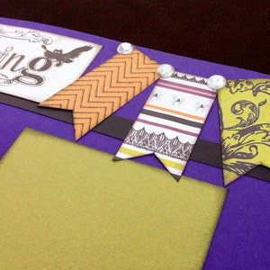May include: Purple scrapbook page with a green, orange, and black patterned paper background. The page has a black and white banner with the text "October 31st, " "Tricking" and "Treating" written on it. There are three decorative paper flags with a black, white, and orange pattern.