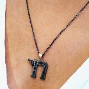 May include: A black chain necklace with a pendant shaped like the Hebrew letter 'Chai' set with black stones.