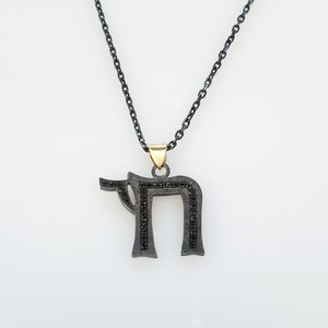 May include: A black chain necklace with a silver pendant in the shape of the Hebrew letter 'Chai' with black diamonds.