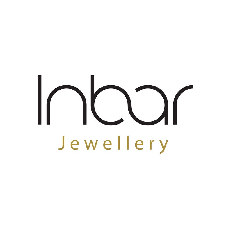 May include: A logo featuring the word Inbar in a black, stylized sans-serif font with a connected 'n' and 'b' character, positioned above the word Jewellery written in a smaller, gold-colored sans-serif font on a plain white background.