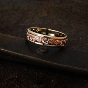 May include: A gold and rose gold wedding band with a floral design.