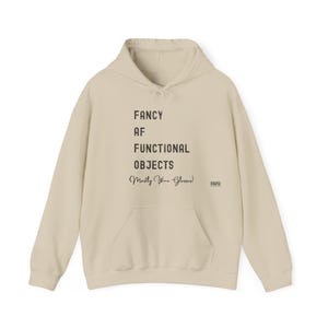 May include: A cream-coloured hoodie with a front pocket and drawstring hood. The front of the hoodie features the text "FANCY AF FUNCTIONAL OBJECTS (Mostly Wine Glasses!)" in black, with the acronym "FAFO" printed on the right side.